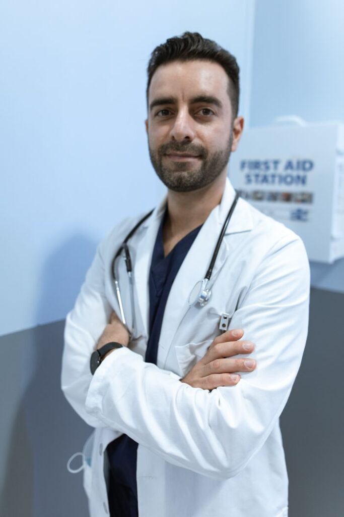 A confident male doctor with crossed arms, wearing a lab coat and stethoscope.